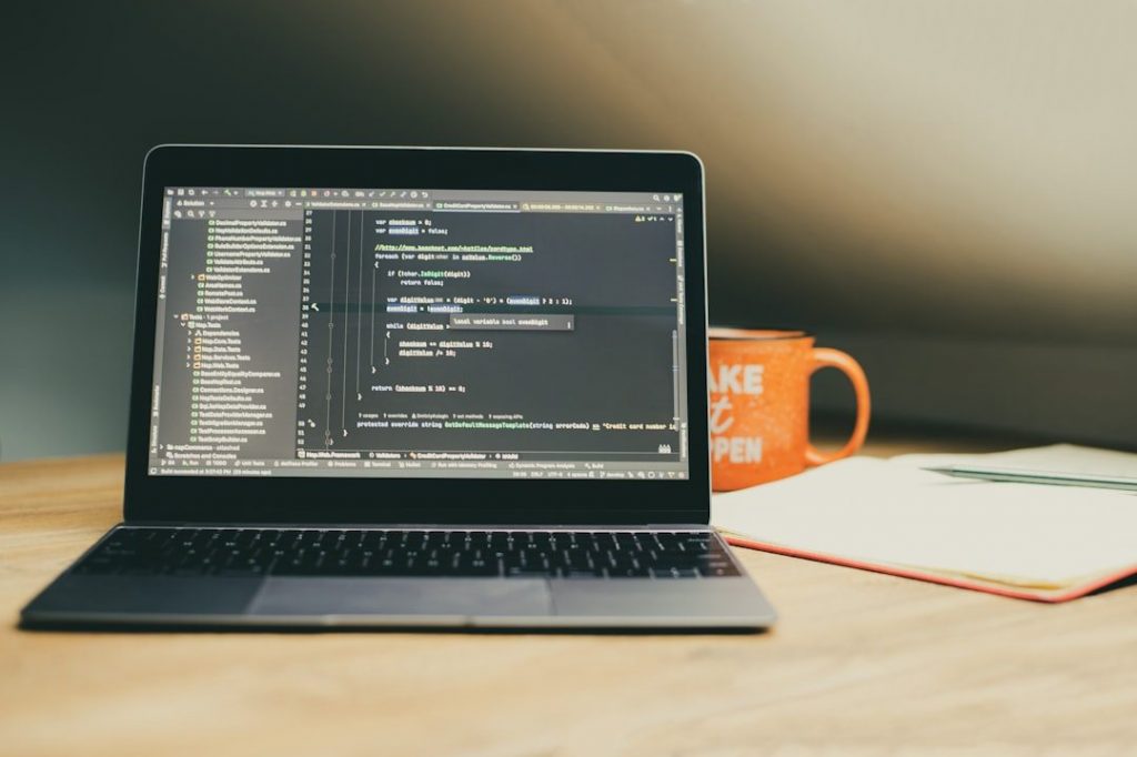 Laptop displaying code with an orange mug nearby