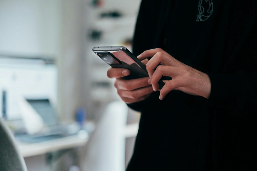 Smartphone mit geöffneter Messenger-Unterhaltung in einer Hand