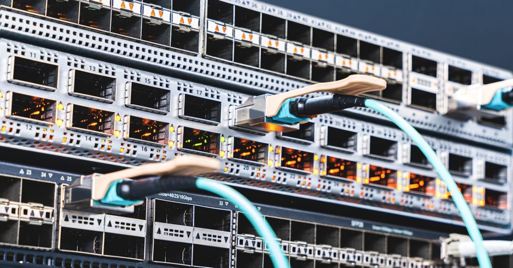 Reihen von Servergestellen mit Verkabelung symbolisieren globale KI-Recheninfrastruktur