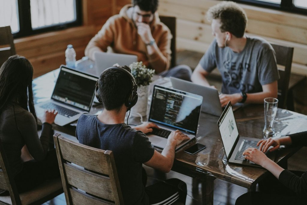 Team bespricht Arbeitsergebnisse an einem Tisch mit Laptops