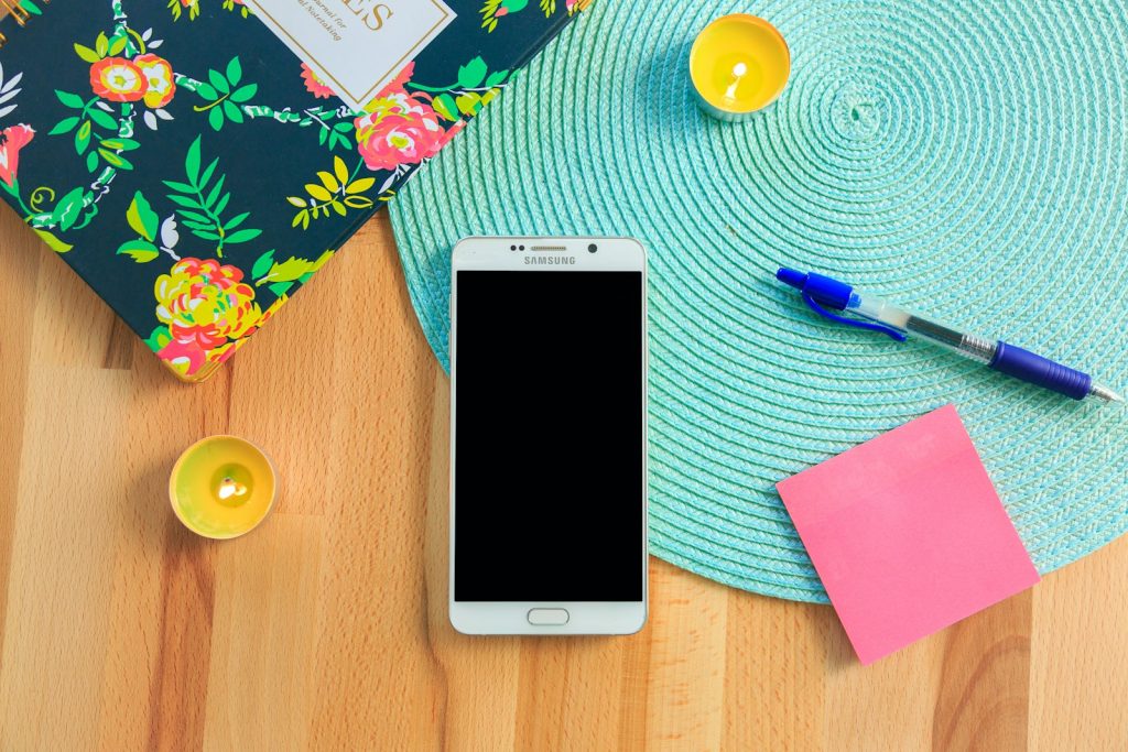 Smartphone neben Notizbuch für sprachgesteuerte Notizen