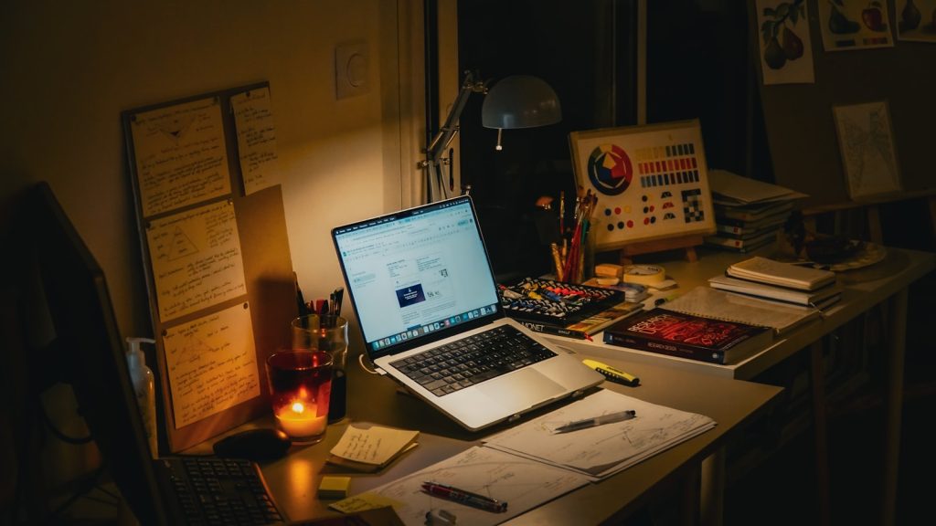 Schreibtisch mit Laptop und geöffnetem E-Mail-Programm in gedämpftem Licht