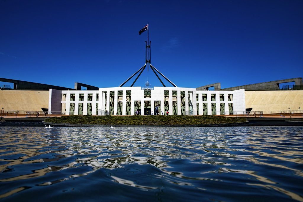 Das Parlamentsgebäude in Canberra mit australischer Flagge unter blauem Himmel