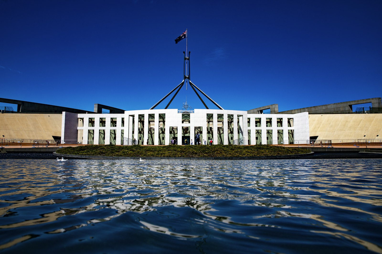 Das Parlamentsgebäude in Canberra mit australischer Flagge unter blauem Himmel