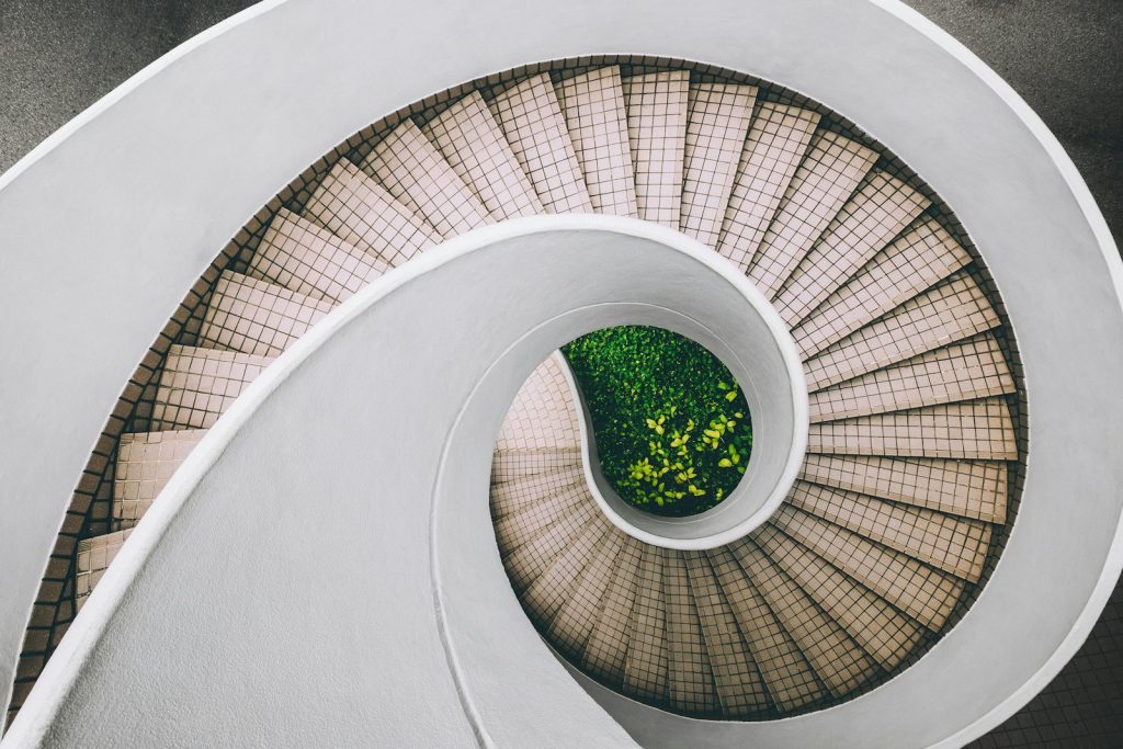 Wendeltreppe von oben fotografiert, als Sinnbild für wiederholte Durchläufe