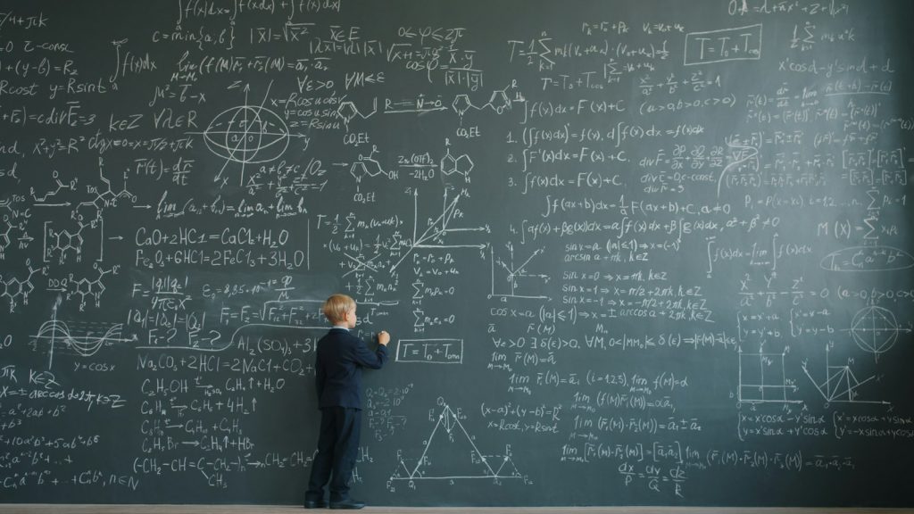 Kind vor einer großen grünen Tafel mit mathematischen Formeln