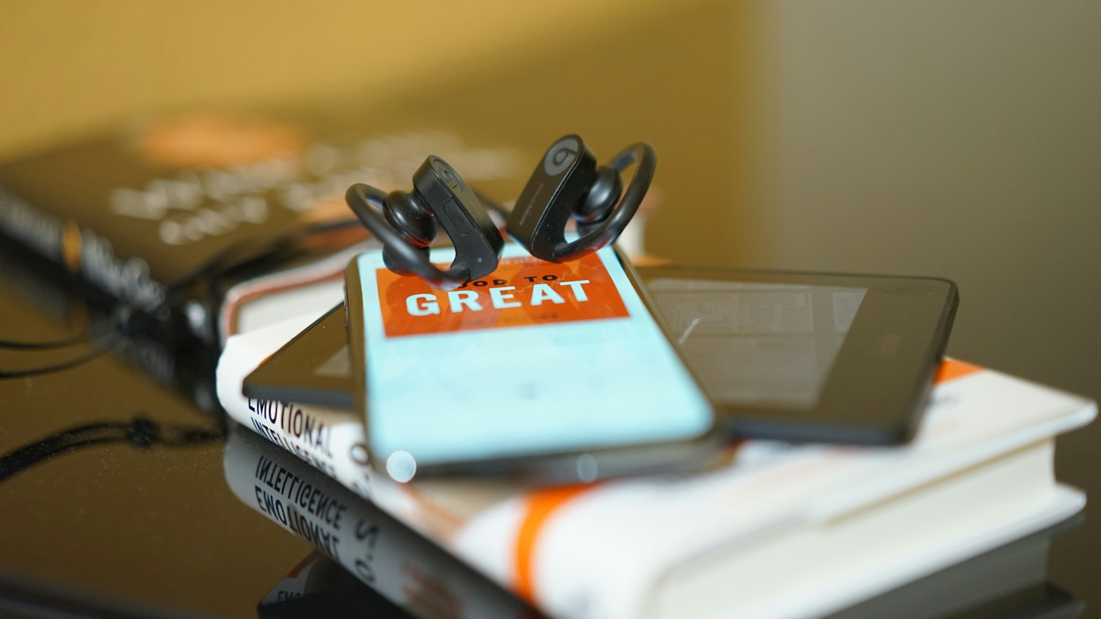 Schwarze Kopfhörer und mobile Geräte auf einem Bücherstapel