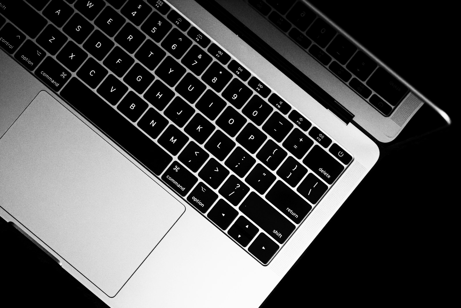 Nahaufnahme einer MacBook-Tastatur und eines Trackpads in Schwarz-Weiß