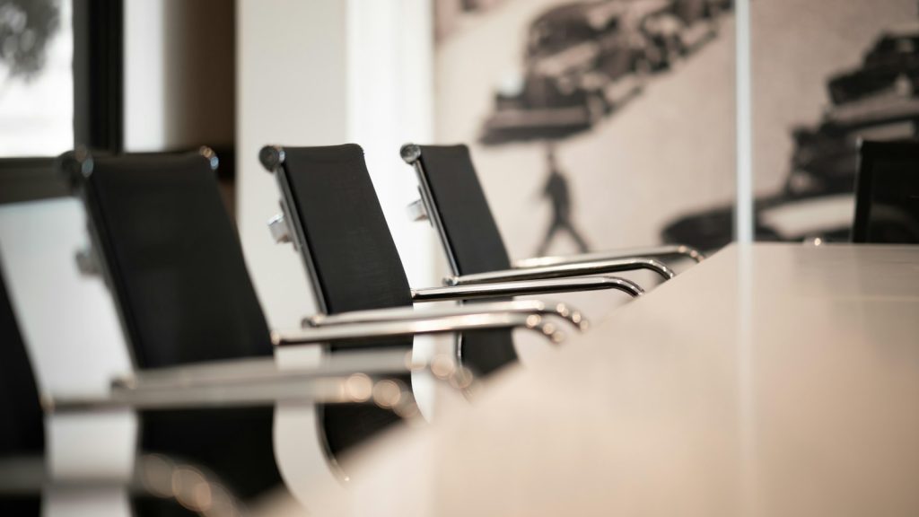 Leere schwarze Bürostühle mit verchromten Armlehnen an einem hellen Konferenztisch