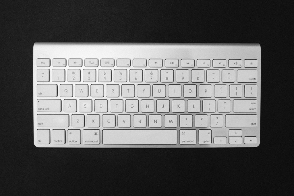 Weiße Computertastatur auf einer dunklen Tischfläche