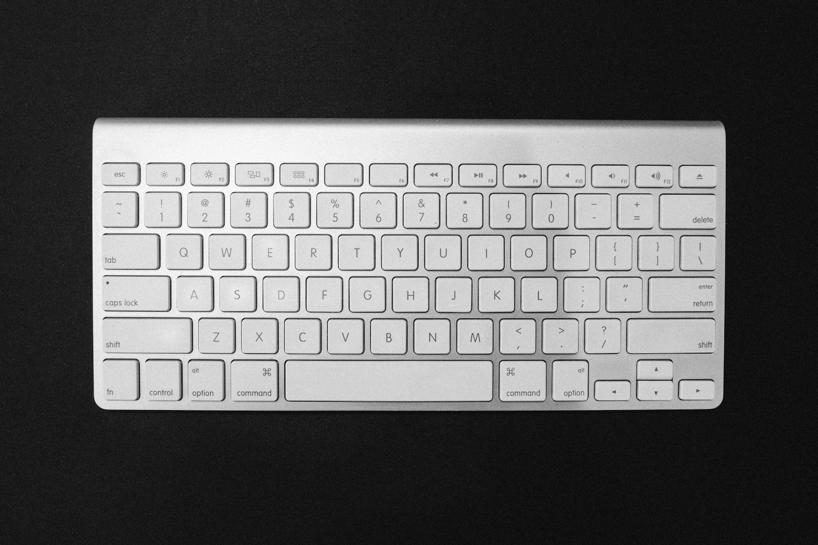 Weiße Computertastatur auf einer dunklen Tischfläche