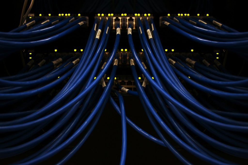 Blaue Netzwerkkabel an einem Rack mit leuchtenden Anschlussanzeigen