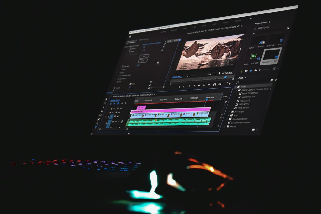 Monitor mit geöffneter Videoschnitt-Software und Zeitleiste in einem dunklen Raum