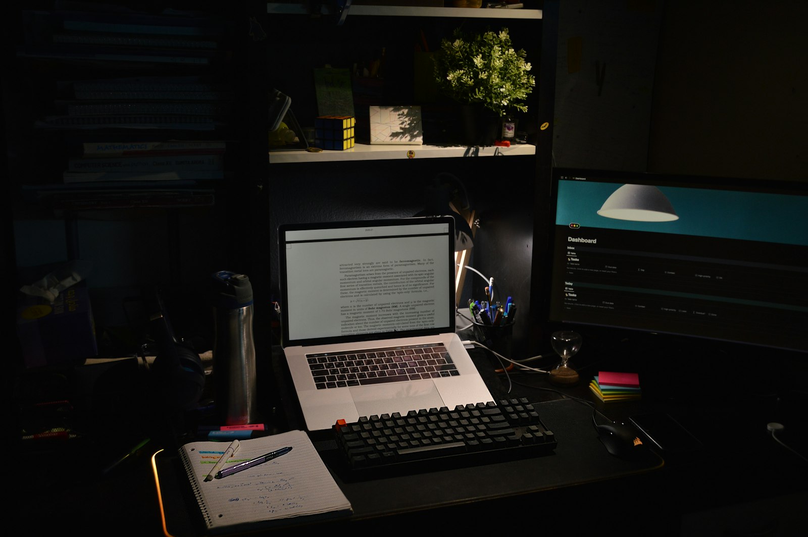 Aufgeklapptes Notebook mit beleuchteter Tastatur auf einem dunklen Schreibtisch